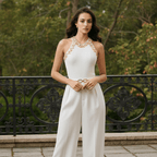 Woman in a white jumpsuit with gold accents standing in a park.