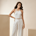 Woman wearing a white jumpsuit with gold accents in a neutral setting