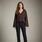 Woman wearing a brown blouse and black pants against a neutral background