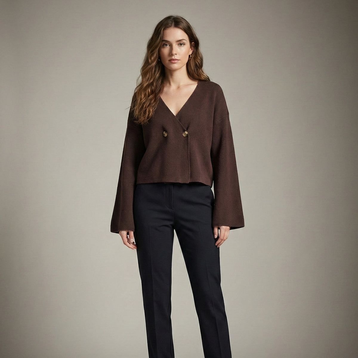 Woman wearing a brown blouse and black pants against a neutral background