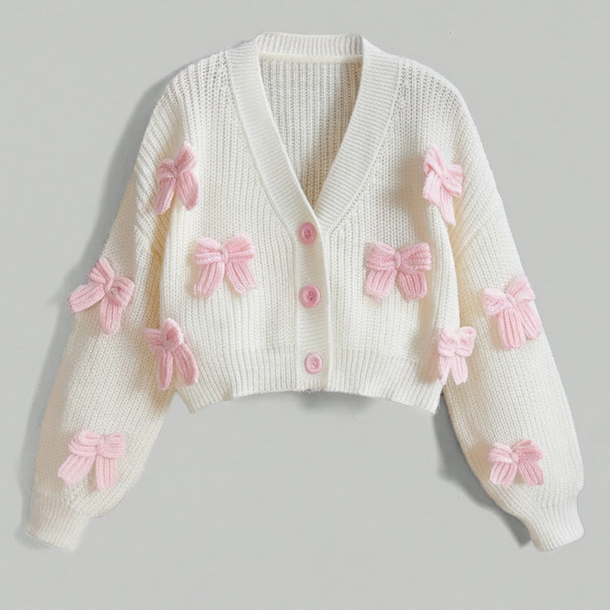 White sweater with pink bows on a gray background