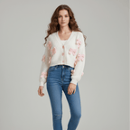 Woman wearing a white sweater with pink bow details and blue jeans on a gray background