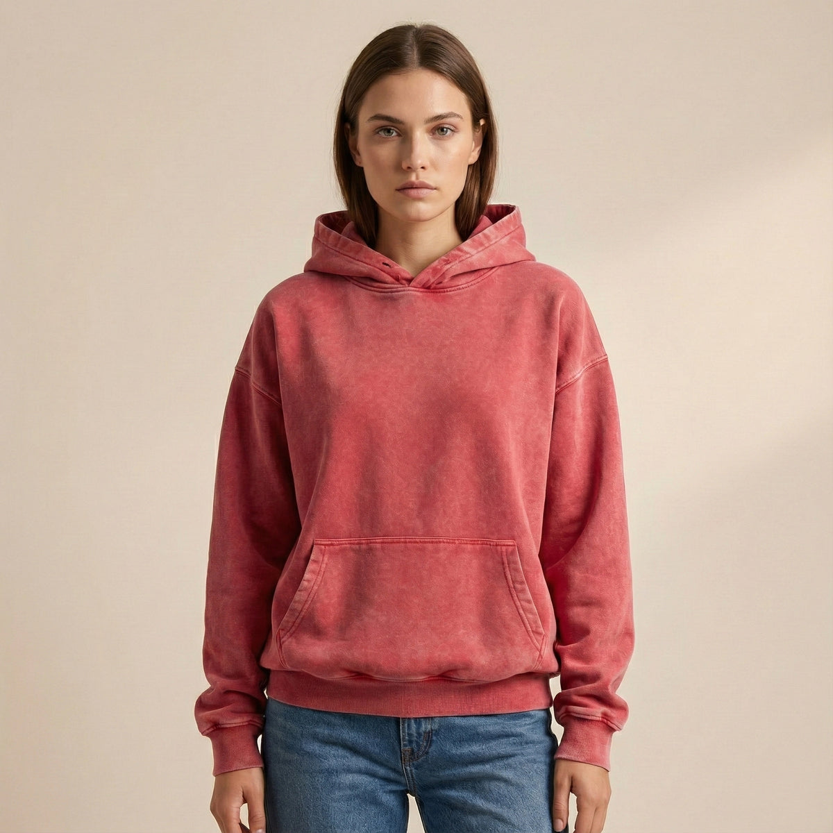 Person wearing a red hoodie and blue jeans on a beige background