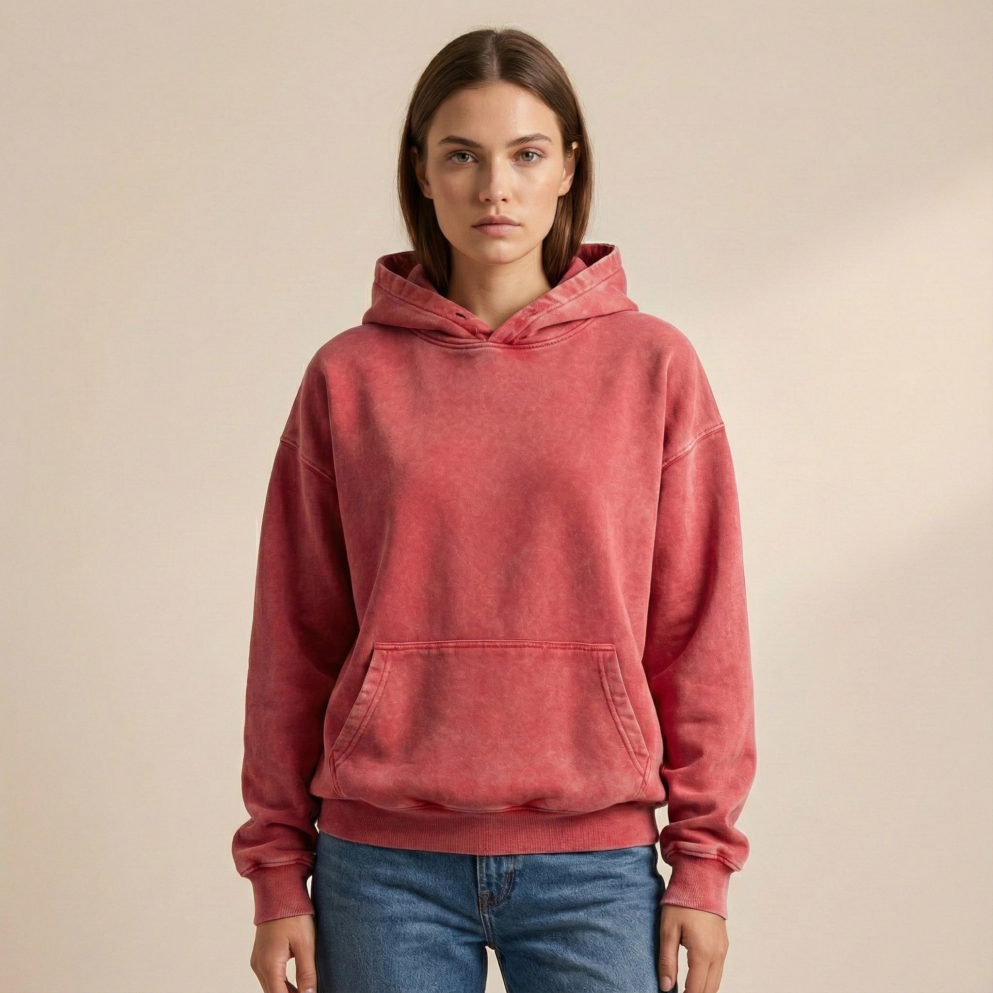 Person wearing a red hoodie and blue jeans on a beige background