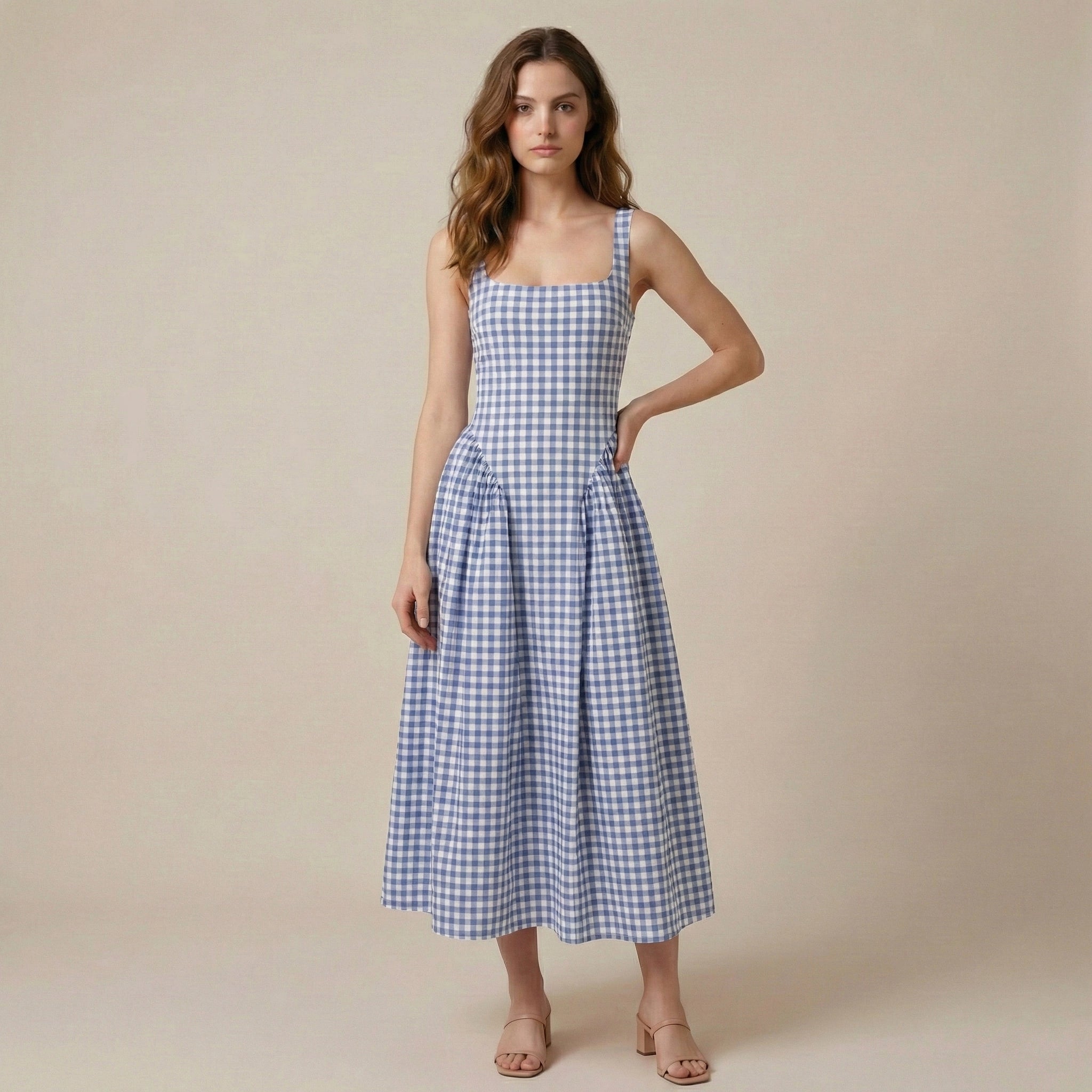 Woman wearing a blue and white checkered dress against a beige background