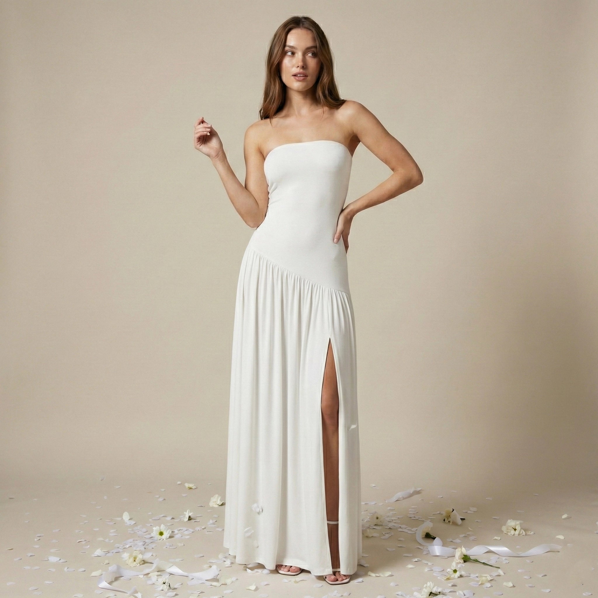 Woman wearing a strapless white gown with a slit on a beige background