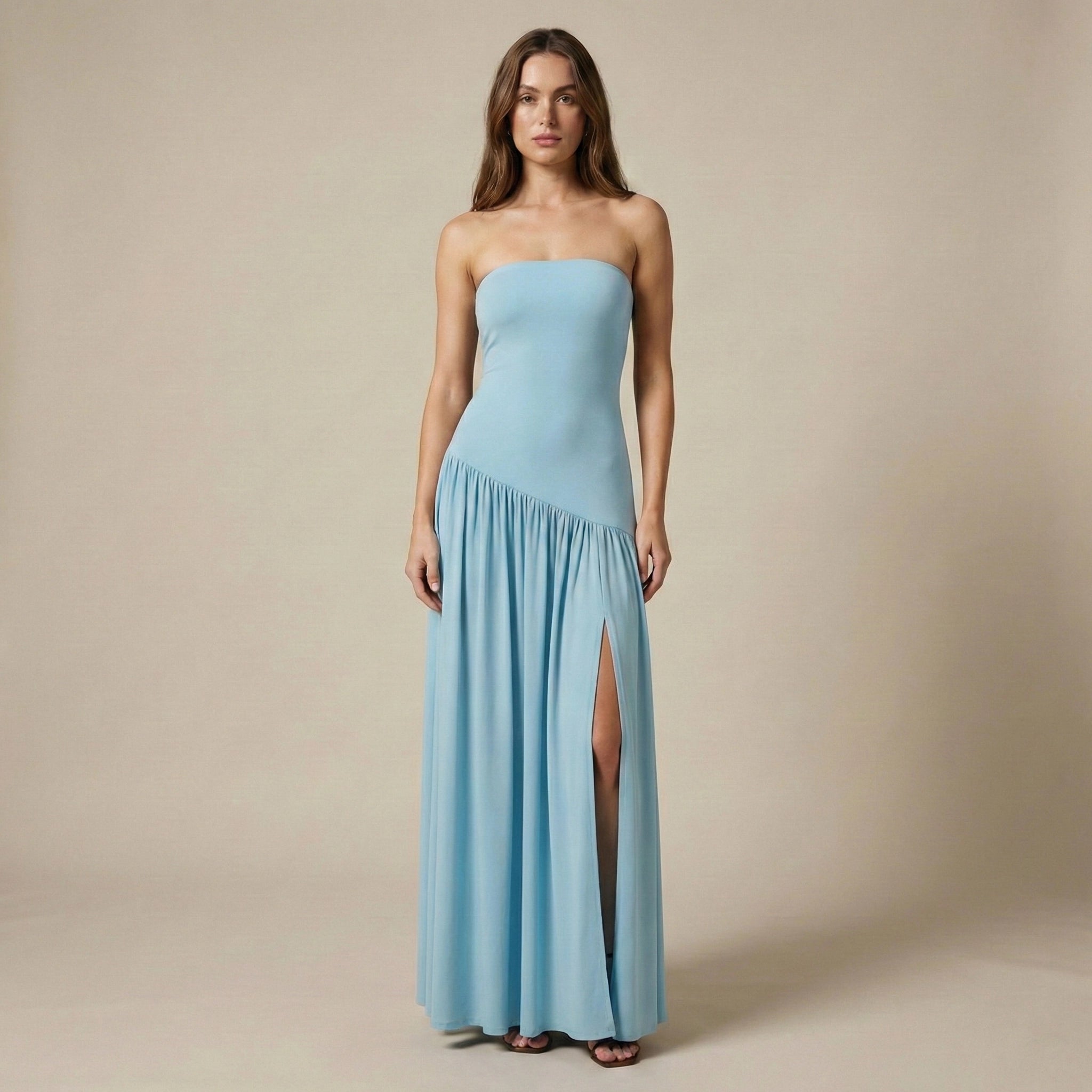 Woman wearing a light blue strapless gown with a slit on a beige background
