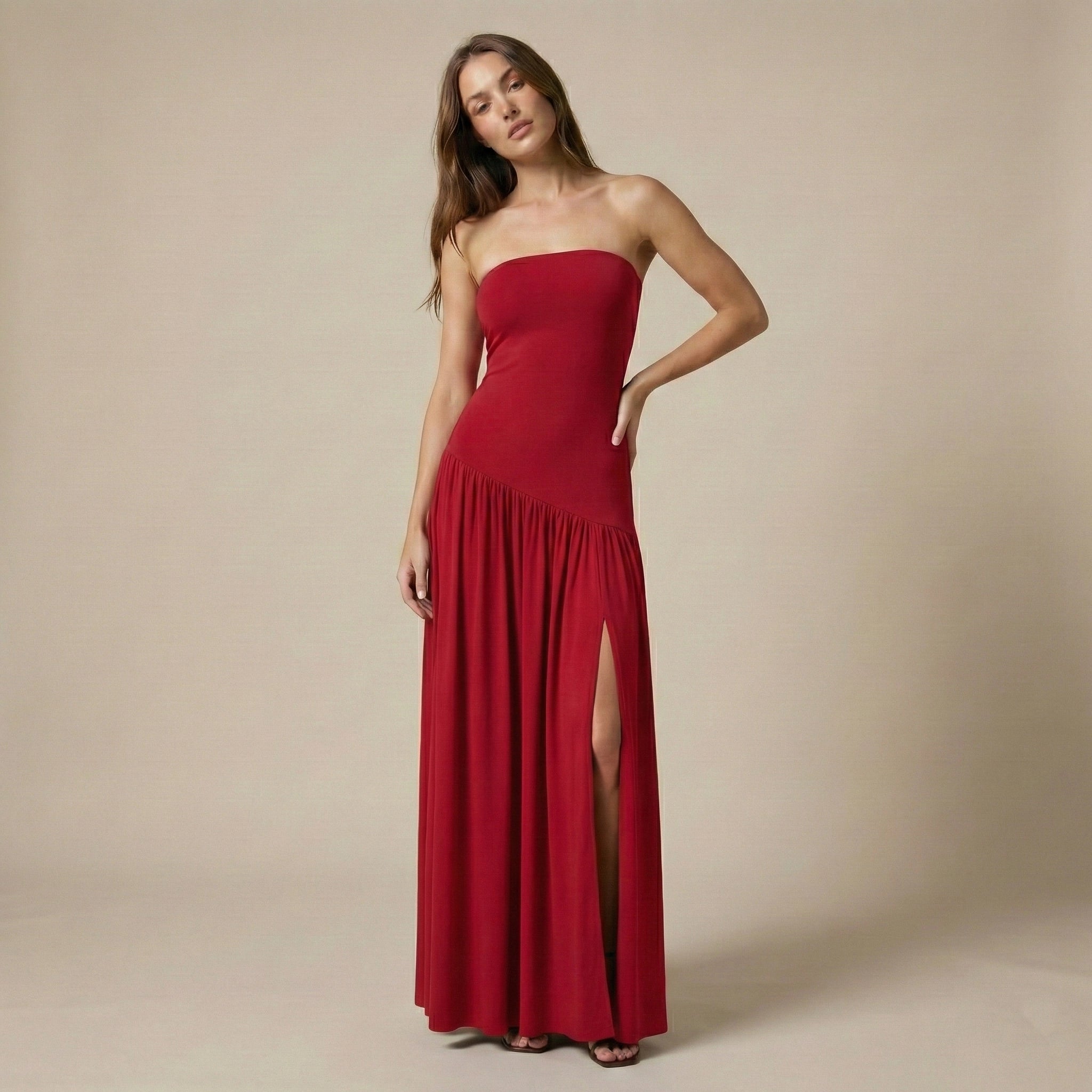 Woman wearing a strapless red dress with a slit on a beige background