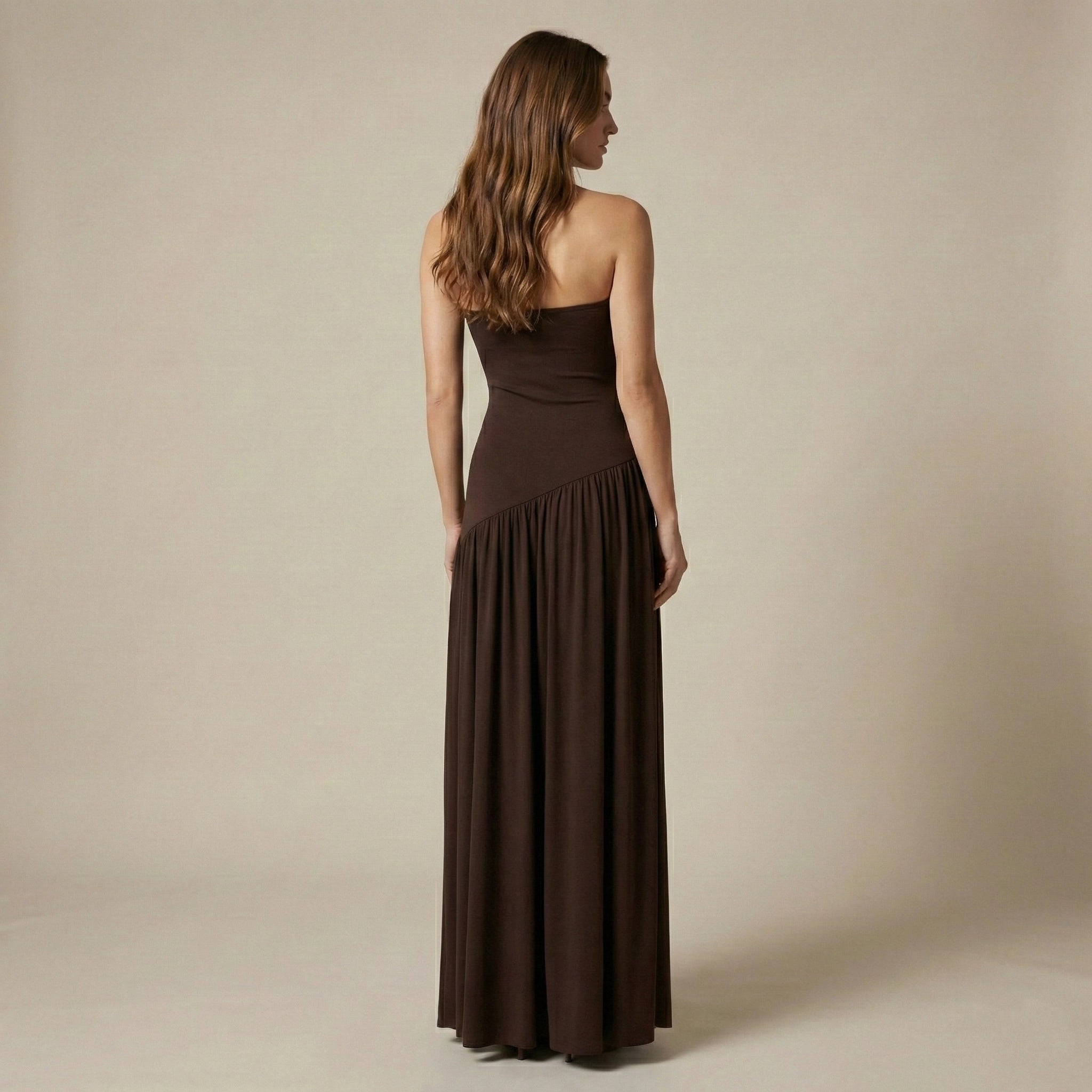 Woman wearing a brown strapless dress against a beige background