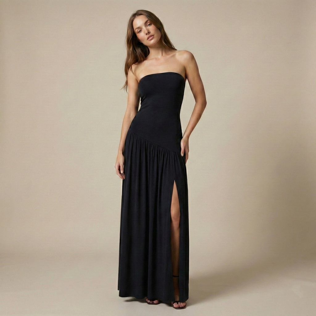 Woman wearing a black strapless gown with a slit on a beige background