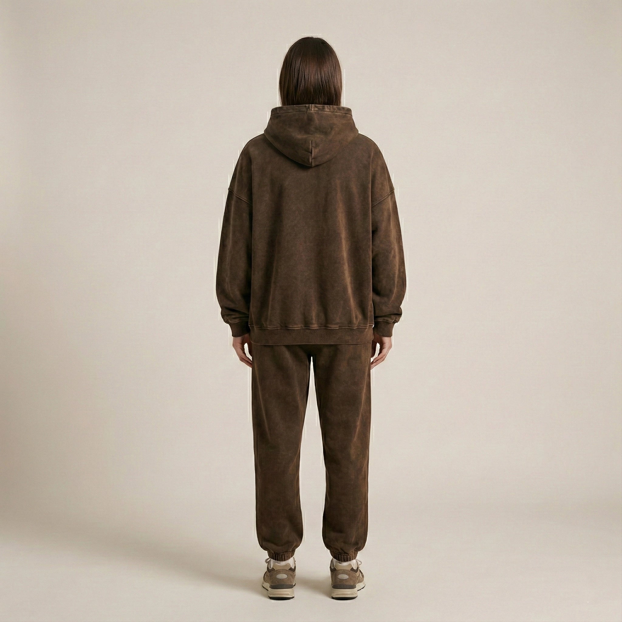 Person wearing a brown tracksuit on a beige background