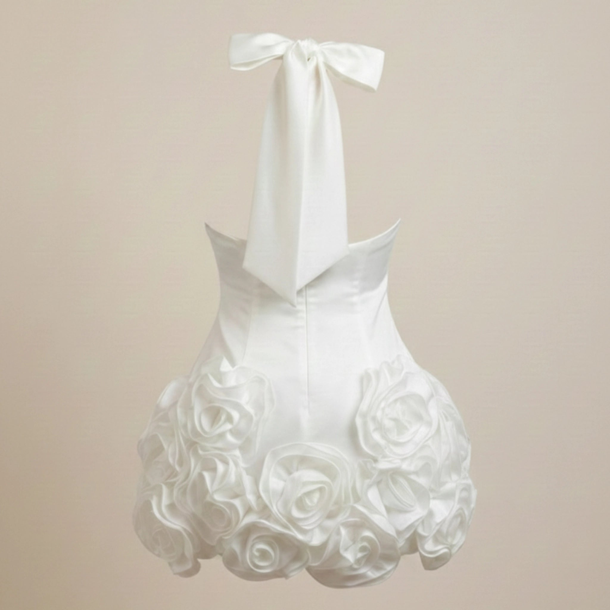 White dress with floral details and a bow on a beige background