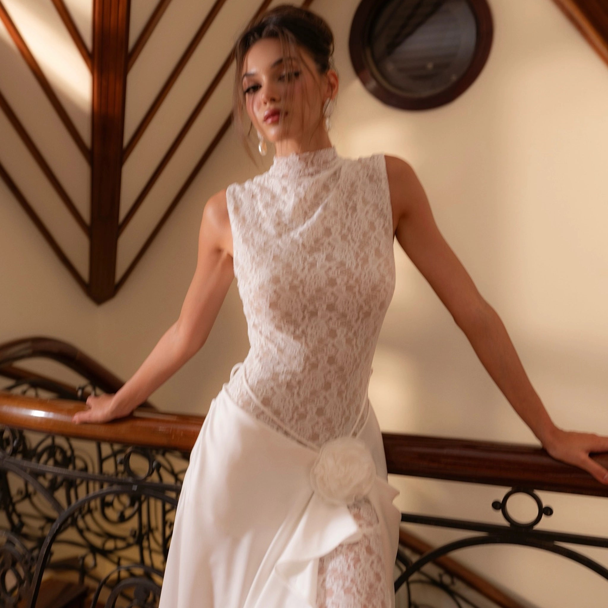 Woman in a white lace dress standing on a staircase