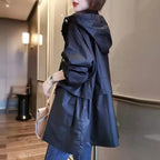 Person wearing a dark blue trench coat in an indoor setting