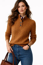 Woman wearing a brown cable knit sweater with a white shirt underneath, holding a brown handbag.