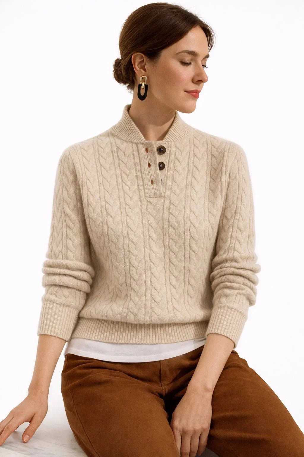 Woman wearing a beige cable knit sweater and brown pants on a white background