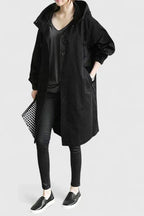Person wearing a long black coat with a hood on a white background