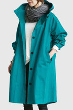 Person wearing a teal raincoat with a plain background