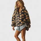 Woman wearing a floral hoodie and denim shorts on a plain background