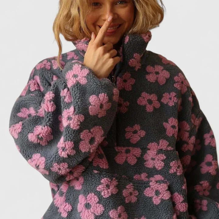 Person wearing a dark gray fleece jacket with pink floral patterns on a white background