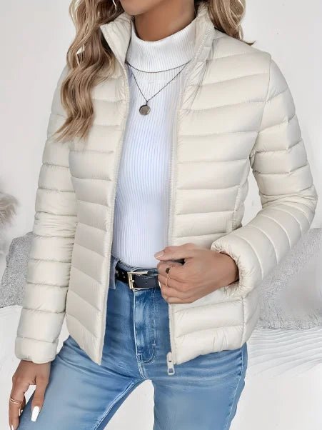 Person wearing a white puffer jacket over a light blue sweater and jeans on a neutral background