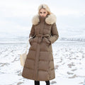 Woman wearing a long brown puffer coat with fur hood in a snowy landscape