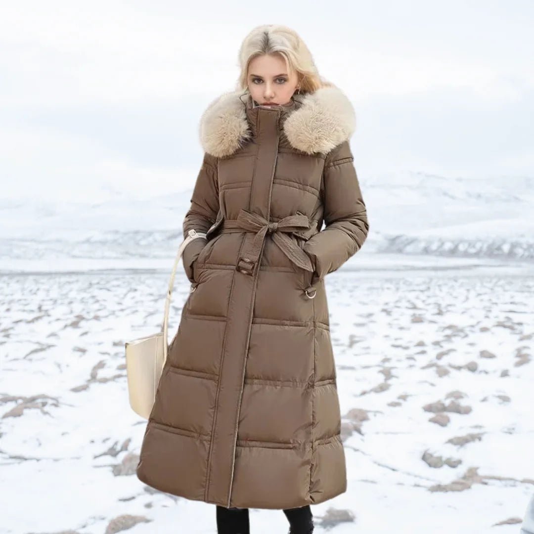 Woman wearing a long brown puffer coat with fur hood in a snowy landscape