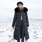Woman wearing a long black puffer coat with a fur hood in a snowy landscape