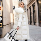 Woman wearing a long white puffer coat with a fur-lined hood on a city street.