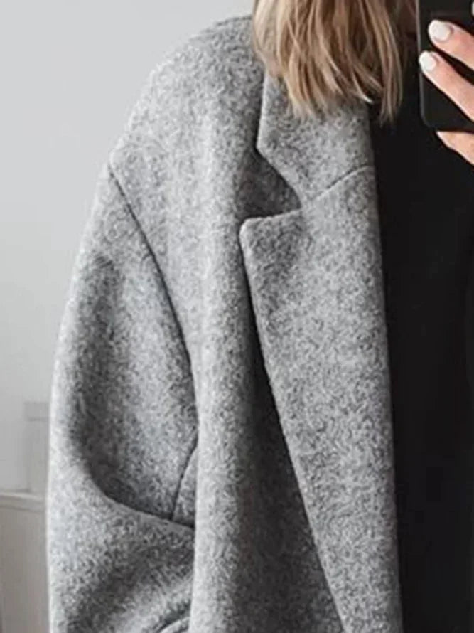 Person wearing a gray coat with a blurred background