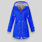 A bright blue hooded raincoat with a black and white striped hood lining, shown against a solid gray background.