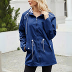 Woman wearing a blue raincoat with white drawstrings in an outdoor setting.