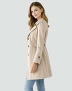 Woman wearing a beige trench coat on a light gray background