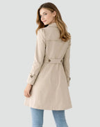 Woman wearing a beige trench coat on a light gray background