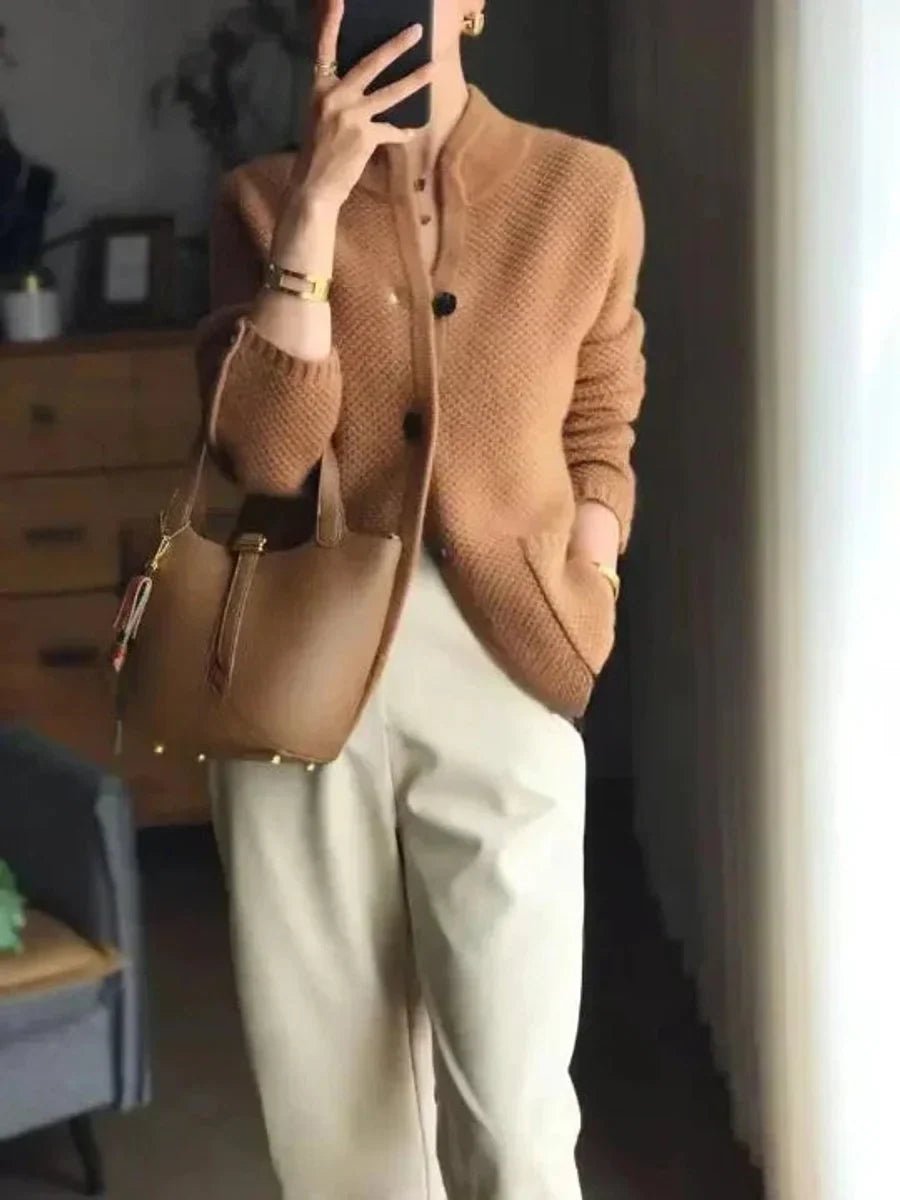 Person wearing a brown cardigan and holding a matching handbag indoors.