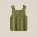 Green knitted tank top with cable pattern on a beige background