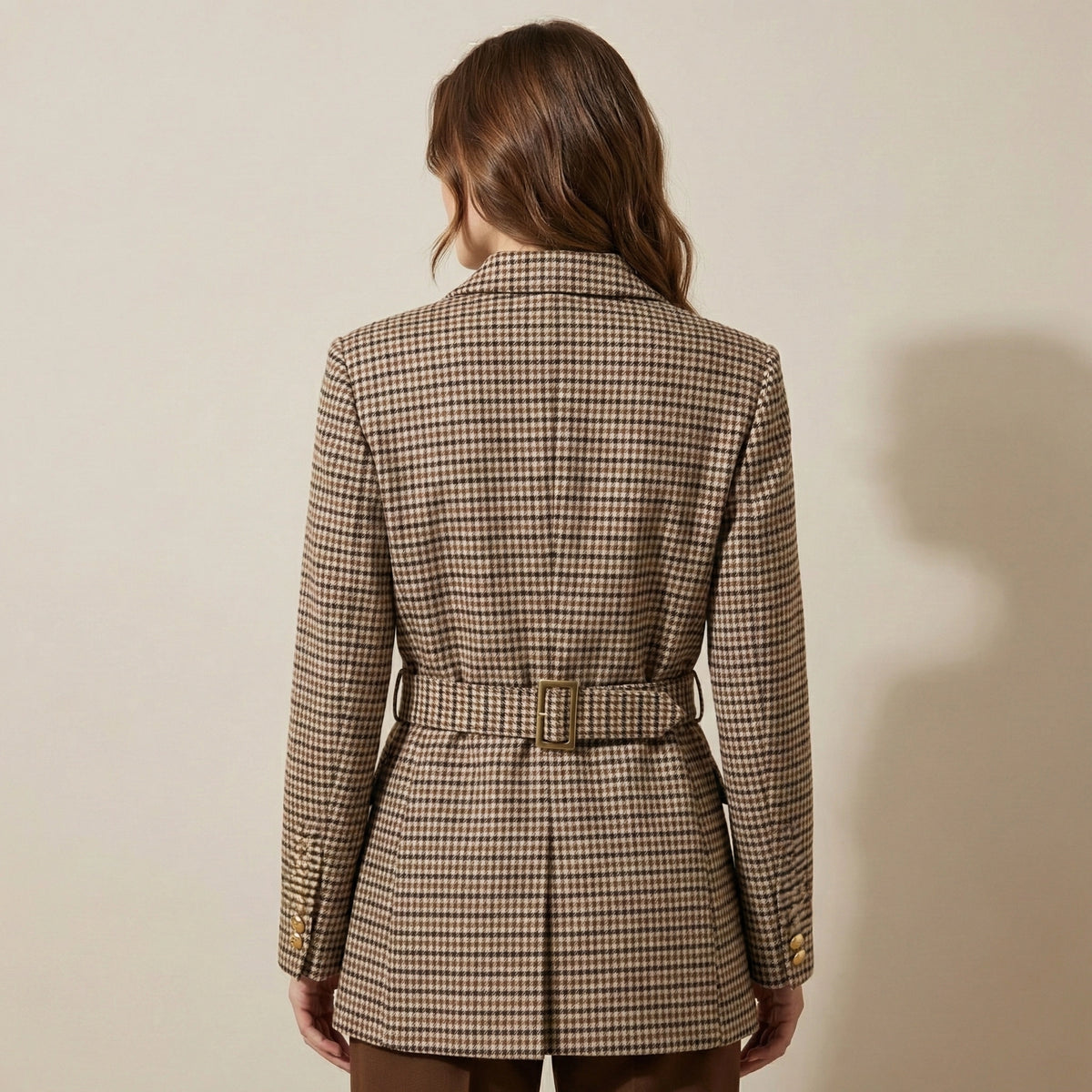 Woman wearing a plaid blazer against a beige background