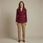 Woman wearing a burgundy blazer and beige pants against a beige background