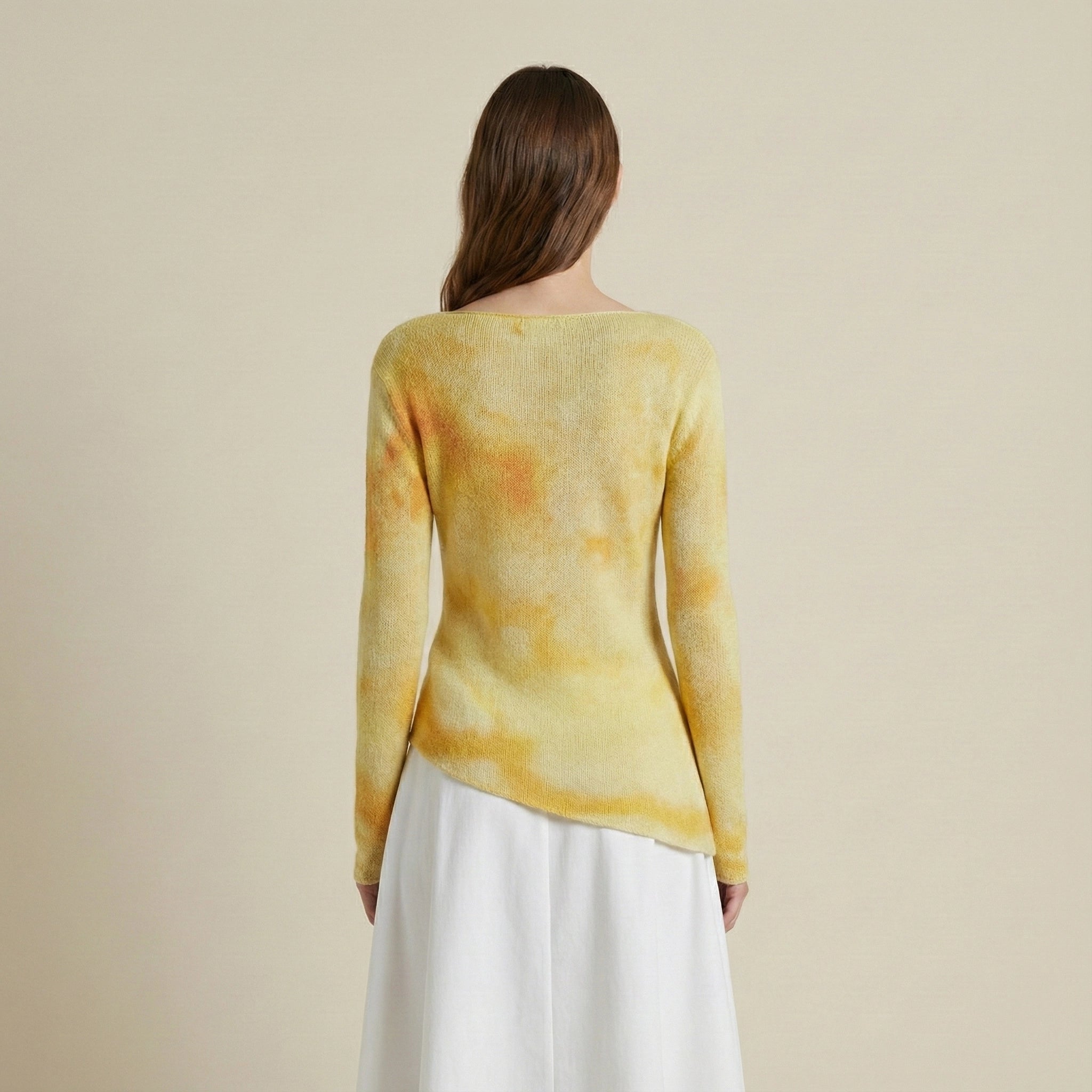 Woman wearing a yellow tie-dye sweater and white pants on a beige background