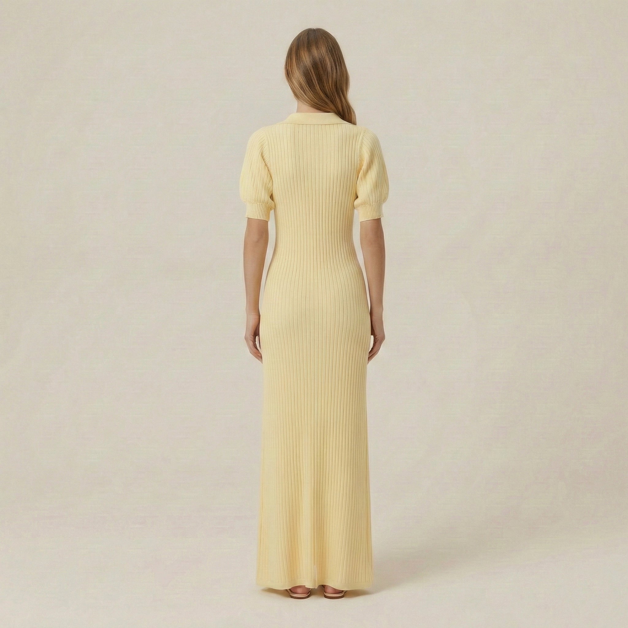 Woman wearing a long yellow dress with a plain background