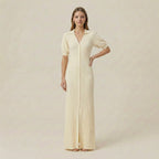 Woman wearing a long, light-colored dress against a plain background