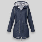 A navy blue hooded raincoat with silver zippers and white-and-black striped lining inside the hood, shown against a solid gray background.
